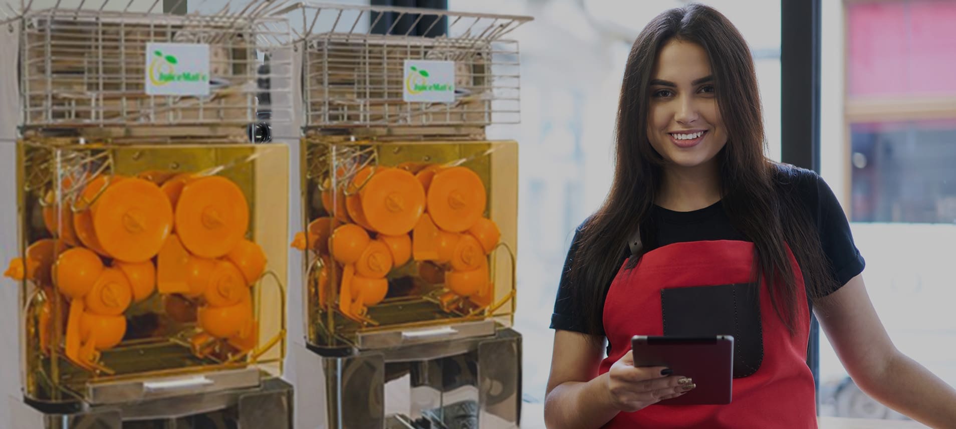 Image of a restaurant using the JM20 to make orange juice with a commercial juicer. Happy employee is watching the machine make orange juice.